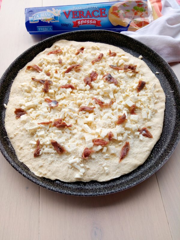 Stendiamo la base per pizza verace, e incominciamo a condire il nostro <b>sfincione</b>  con il caciocavallo, il pecorino grattugiato le acciughe spezzettate.