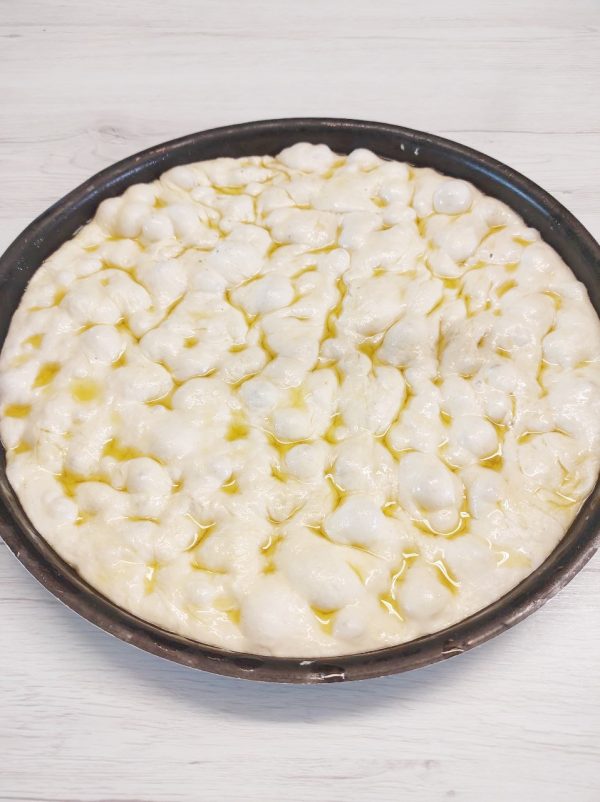 Prima di mettere in forno le focacce con i polpastrelli delle dita unti facciamo le fossette su tutto l'impasto e mettiamo l'emulsione.